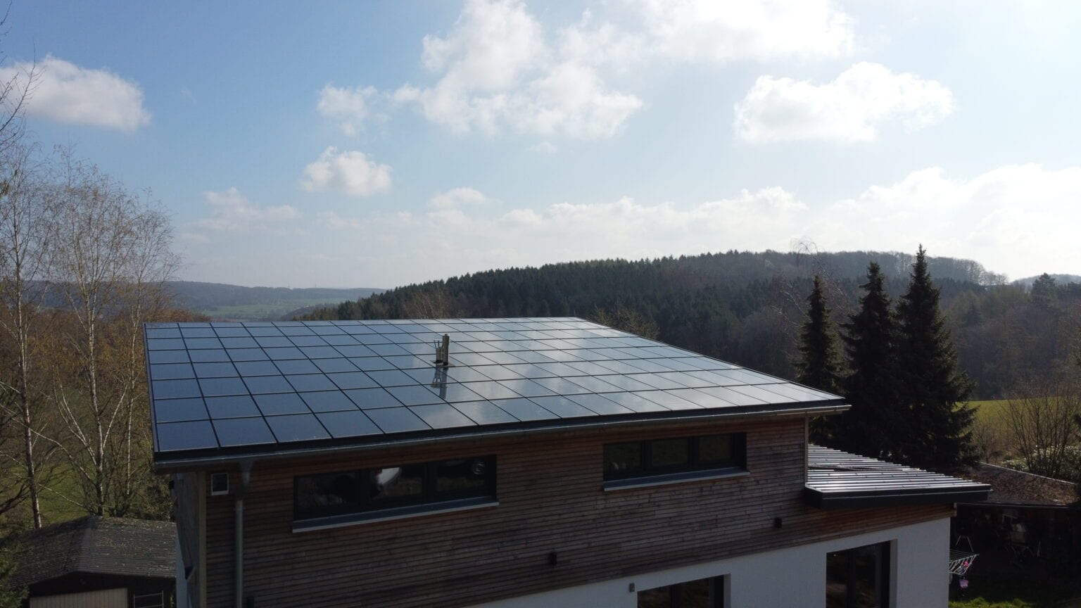 Ennogie-Solardach in Osnabrück: Dachfläche mit Photovoltaikmodulen im Vordergrund, blauer Himmel und Berge im Hintergrund