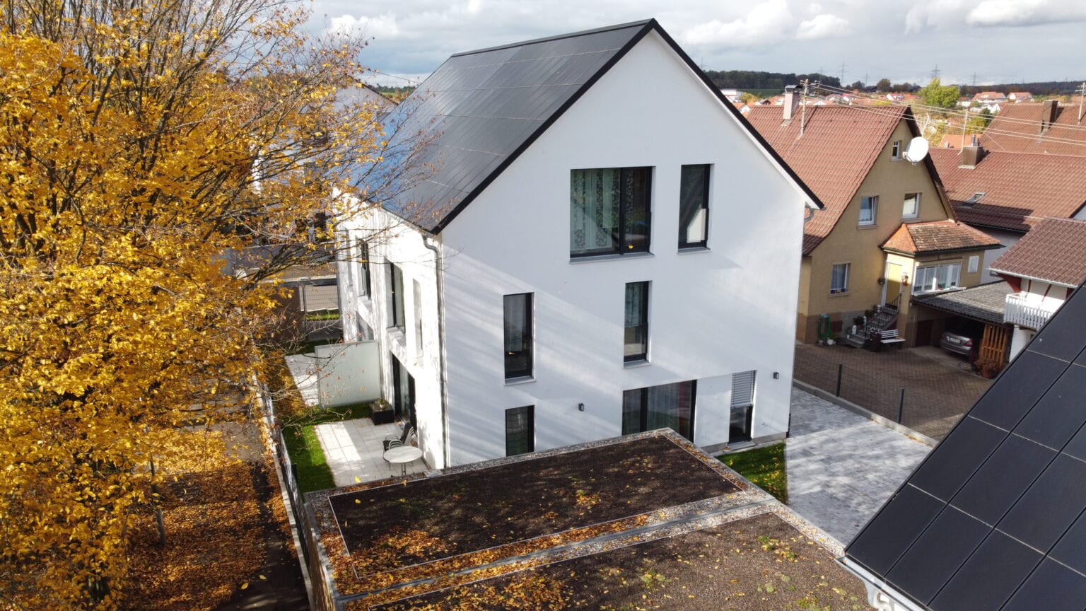 Ennogie-Solardach in Freiberg: Eine vollflächige Dachfläche belegt mit Ganzdachlösung für Photovoltaik zu erkennen, Baum in Vordergrund