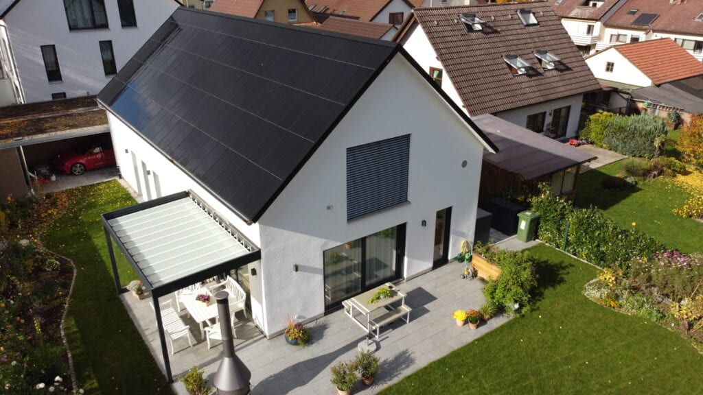 Ennogie-Solardach in Freiberg: Einheitliche Dachfläche mit Photovoltaikmodulen, Garten und Terrasse im Vordergrund