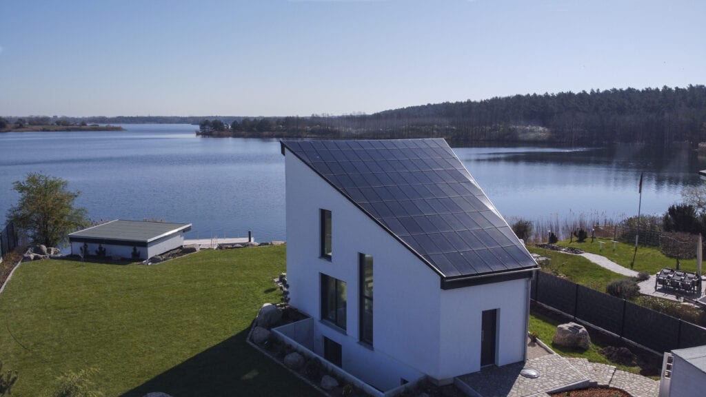 Ennogie-Solardach in Niegripp: Haus mit angeschnittener Dachfläche im Vordergrund, See im Hintergrund