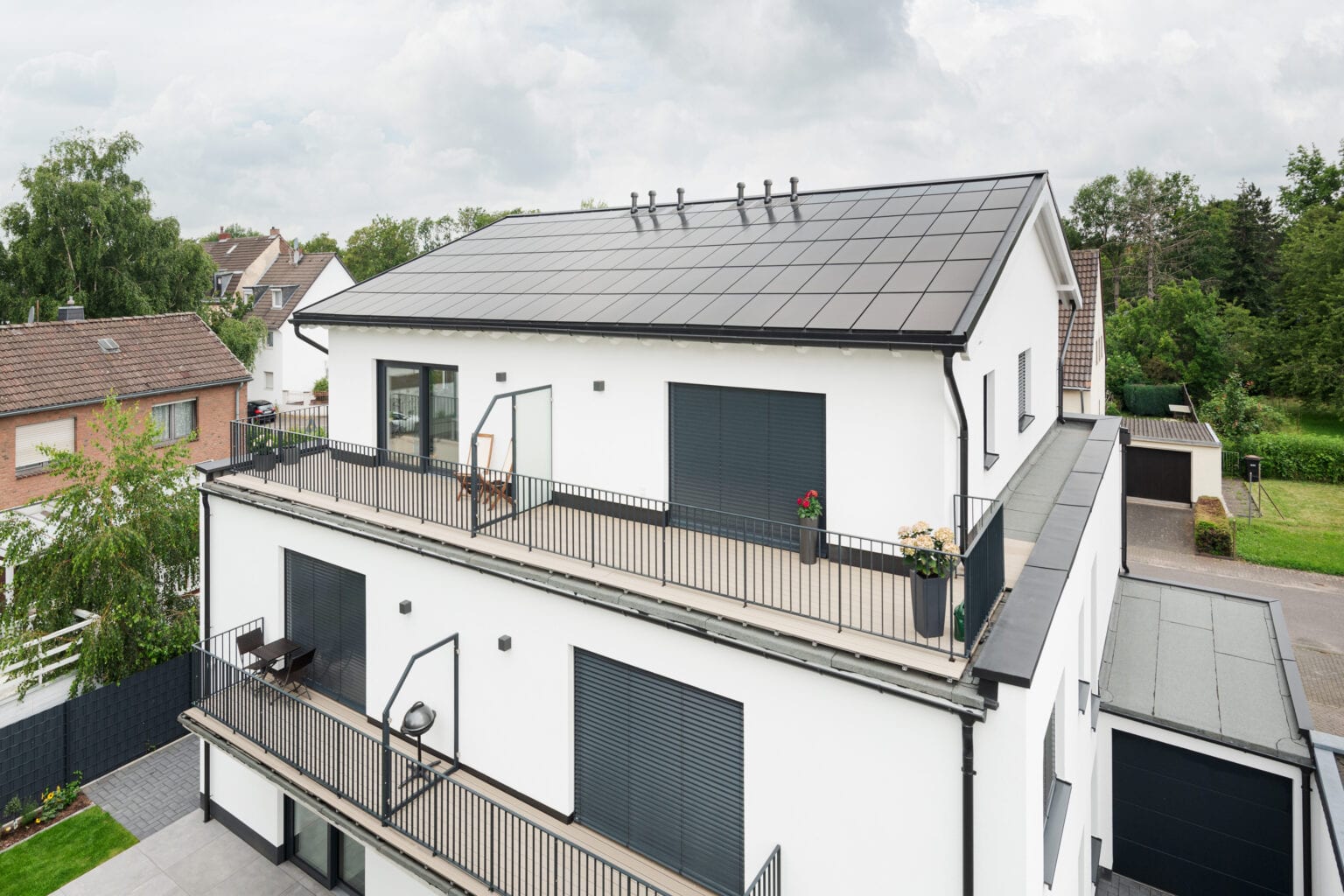 Ennogie-Solardach auf Neubau in Köln: Fokus auf homogener Dachfläche inklusive Lüftungen, Balkone und Garage zu erkennen