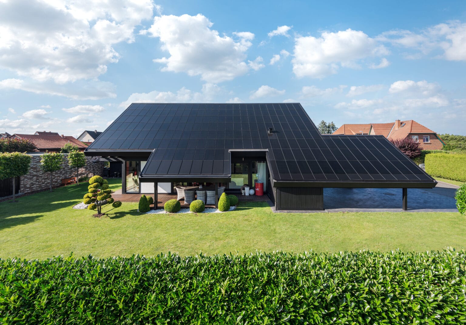 Ennogie-Solardach in Nienburg: Blick auf Dachüberstände, Carport und Garten mit Bäumen und Sträuchern