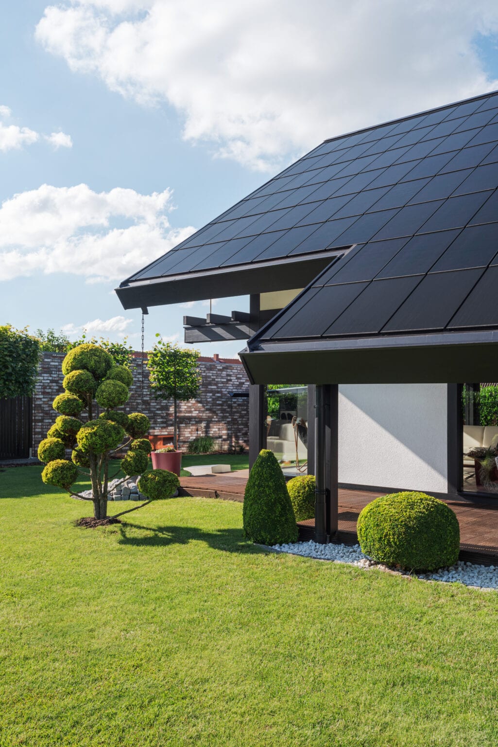 Detailaufnahme Ennogie-Solardach in Nienburg inklusive Terrasse mit Bäumen und Sträuchern im Vordergrund