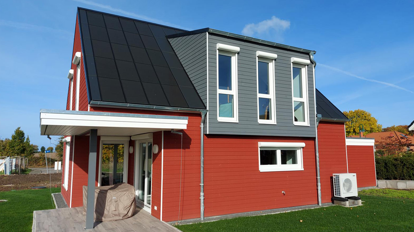Nachhaltiges rotes Holzhaus mit Ennogie-Solardach von Architekt Lutze