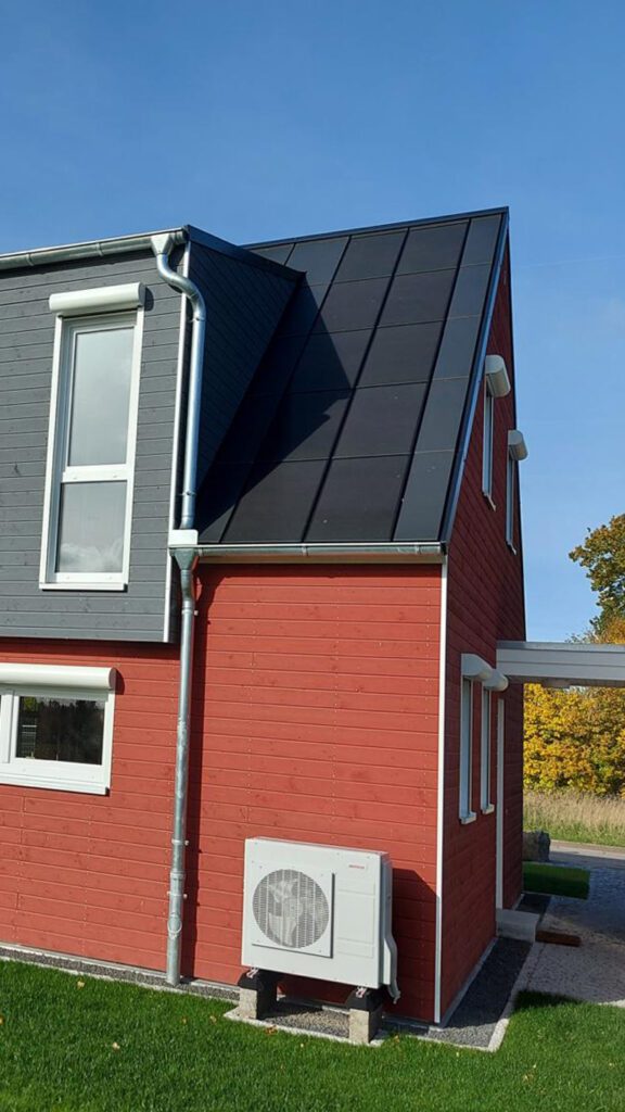 Nahaufnahme: Nachhaltiges rotes Holzhaus mit Ennogie-Solardach von Architekt Lutze